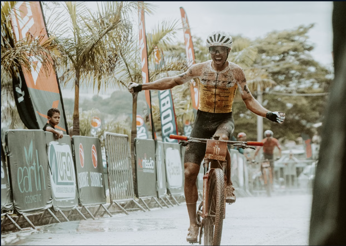 Cyclist celebrates victory as he crosses the finish line in a vibrant outdoor race event.