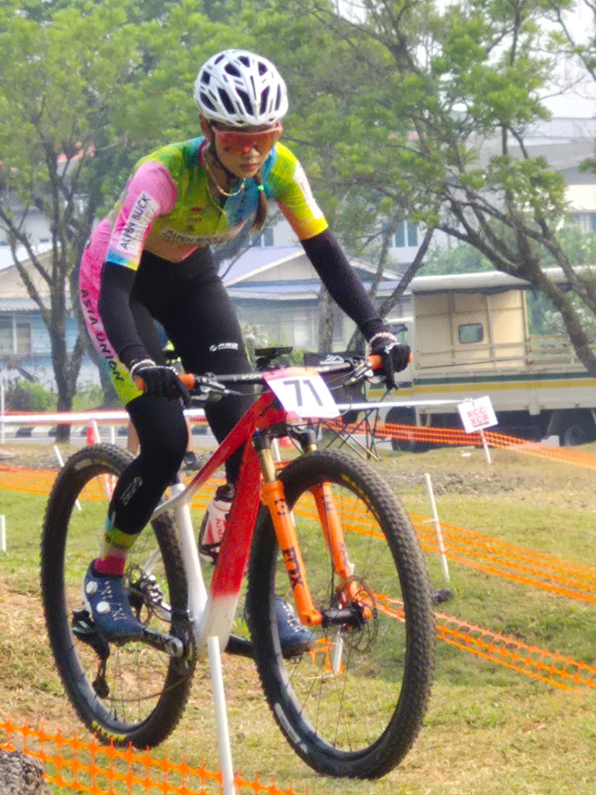 Female mountain bike racer riding on a grassy course.